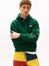 Buzo verde con capucha y cordón distintivo, bolsillo canguro, puños y bajo de punto canalé, logo oversize de Tommy Hilfiger en la manga y la parte trasera, parche con logo de Tommy Hilfiger en el pecho y detalles distintivos de Hilfiger Sailing.