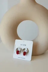 Aros de acero quirúrgico hipoalergénico con forma de argolla plateada y dije circular colgante de piedra natural color azul.