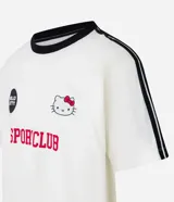 Remera blanca de corte boxy con cuello redondo y detalles en negro. Estampado frontal con logo de Hello Kitty y texto "Sport Club".