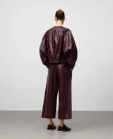 Chaqueta bomber de piel sintética color burdeos, con cuello redondo, manga japonesa ancha con puño elástico y bajo elástico. Cierre frontal con cremallera.