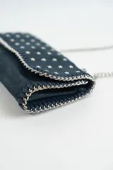 Cartera bandolera azul con tachas plateadas en forma de estrella, correa de cadena plateada y asa corta de cuero.