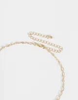 Collar corto dorado con cadena de eslabones combinados y dijes colgantes de frutilla rosa brillante, hongo dorado, moño dorado y perla.