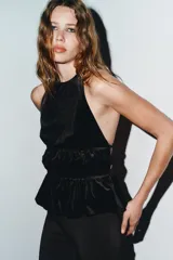 Top negro de terciopelo con cuello halter ajustable con gancho metálico, detalle de frunces en el delantero, espalda descubierta con tira cruzada y cierre lateral con cremallera oculta.