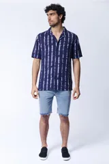 Camisa de manga corta para hombre confeccionada en viscosa, con estampa de arabescos en color azul y blanco. Presenta cuello con solapa y cierre frontal mediante botones.