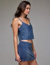 Top corto de denim azul con apliques de strass plateados distribuidos por toda la prenda. Presenta un escote en V y breteles finos, también adornados con strass.