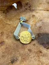 Pulsera dorada con dije circular con la figura del Espíritu Santo y banda de terciopelo verde.