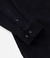 Camisa de hombre de manga larga, color verde oscuro, confeccionada en terciopelo, con cuello clásico y dos bolsillos frontales con tapa y botón.