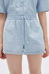 Short celeste de jean con cintura elastizada y cordón ajustable. Presenta apliques de strass plateados.