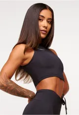 Top deportivo blanco de corte cropped, con cuello alto y logo estampado en el frente.