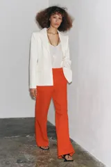 Pantalón de tiro alto color naranja, corte wide leg y largo hasta el tobillo. Tiene bolsillos de parche delanteros y cierre frontal con cremallera y botón.