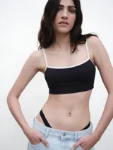 Top deportivo negro con estampado de rayas verticales blancas y tirantes finos.