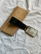 Cinturón negro con hebilla rectangular con diseño de cuerno.