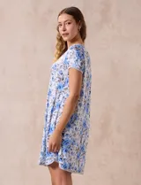 Camisón corto de tejido suave con estampado floral en tonos celeste y azul. Tiene mangas cortas, escote redondo con ribete gris y detalle plisado en el delantero.