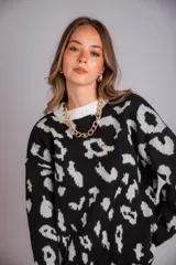 Buzo de punto color negro con estampado animal print en gris claro, de corte holgado y manga larga.