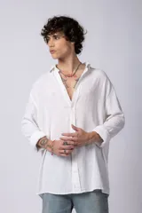 Camisa blanca de lino con cuello clásico, manga larga con puños abotonados y corte holgado. 