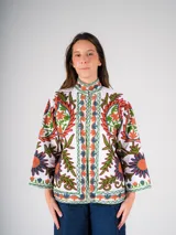 Chaqueta blanca de algodón con bordado floral multicolor de estilo Suzani. Tiene cuello mao, mangas 3/4 y cierre frontal con botones.