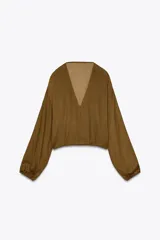 Blusa color marrón con escote en pico, manga larga abullonada con elástico en los puños y volantes en el escote y mangas.