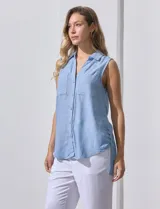 Camisa sin mangas color celeste, confeccionada en lino. Presenta cuello camisero, escote en V, abertura frontal con botones, dos bolsillos de parche en el pecho y terminación con botones en los laterales.