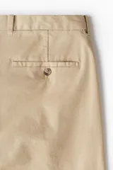 Pantalón chino color beige, de corte slim fit, con bolsillos laterales y traseros.