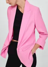 Blazer rosa con solapas de muesca, cierre con dos botones y mangas largas con puños abotonados.