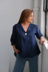 Blusa azul marino con cuello en V, manga 3/4 y cierre frontal con un botón. Presenta bordados con motivos florales.