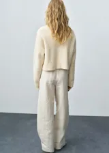 Sweater color crema de punto grueso con cuello alto.