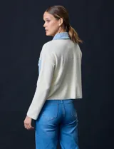 Campera combinada de punto color crema con detalles en denim celeste. Tiene cuello con solapa, cierre frontal con botones metálicos, bolsillos delanteros y corte recto.
