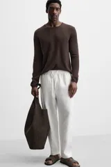 Pantalón de lino color marrón oscuro, de corte recto y relaxed fit. Tiene cintura elástica ajustable con cordón, bolsillos frontales y traseros de parche.