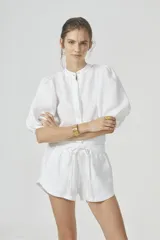 Camisa blanca de lino con cuello mao, mangas globo al codo y botones de nácar.