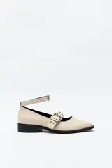 Zapato tipo zueco negro charol con punta fina, doble tira con hebillas metálicas y pulsera al tobillo con tachas.