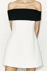 Minivestido blanco con escote recto palabra de honor con banda superior negra fruncida, corte ajustado y cierre lateral con cremallera oculta.
