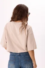 Remera color beige de corte amplio con mangas cortas y cuello redondo. Estampado frontal con la palabra "Monaco" en la parte superior y una fotografía en blanco y negro con la frase "Mont Carlo" en la parte inferior.