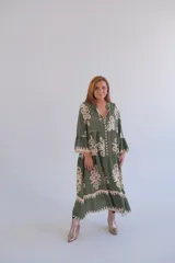 Vestido largo verde con estampado floral en color beige, corte amplio, cuello en V y mangas 3/4 con volantes.