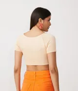 Blusa cropped color crema de viscosa con manga corta, escote en V, fruncido en el busto y abertura en el abdomen.