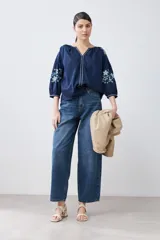 Blusa blanca de estilo boho con bordados de flores en amarillo y azul en mangas y escote.