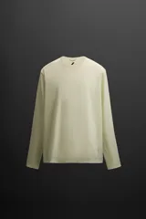 Camiseta deportiva de manga larga color amarillo pálido, confeccionada en tejido técnico perforado, ligero y elástico.