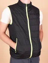 Chaleco negro acolchado con cierre frontal y ribete amarillo flúor en cuello, sisas y bolsillos.