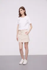 Minifalda color beige con botones plateados al frente y bolsillos delanteros.