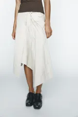Falda midi color crema, de corte asimétrico y diseño cruzado con lazos laterales.
