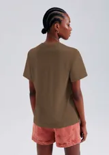 Remera color beige de corte clásico, con cuello redondo y mangas cortas.