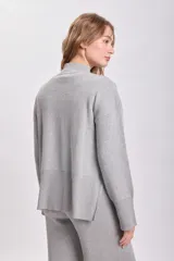 Sweater de punto color gris claro, de cuello alto y corte holgado.