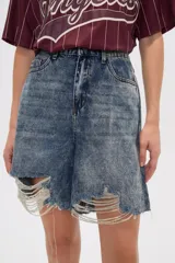 Bermuda de jean celeste con efecto lavado, corte ancho, calce alto y roturas con hilos en el ruedo.