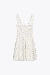 Vestido corto blanco con estampado floral en tonos violeta, escote recto y tirantes anchos.