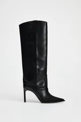 Bota alta de cuero negro con puntera fina y tacón de aguja. Diseño estilo cowboy con paneles combinados de cuero liso y gamuza.
