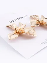 Aros colgantes dorados con forma de flor de cuatro pétalos y centro texturizado.