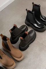 Botas de cuero color marrón con diseño elegante y suela gruesa, ideales para un look moderno.