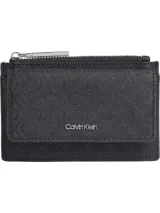 Tarjetero tipo billetera plegable de color negro, con textura grabada en patrón diagonal. Presenta un bolsillo superior con cierre de cremallera metálico y una solapa frontal con el logo metálico de Calvin Klein.