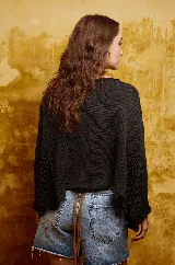 Sweater negro de algodón tejido a mano con apliques de crochet en los laterales y cuello bote amplio.