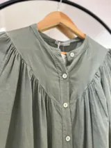 Camisa verde oliva de manga larga con puño, cuello mao y cierre frontal con botones.