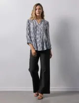 Blusa de gasa estampada con cuello a la base, escote en V y abertura central con botones. Delantera con plisados y mangas 3/4 regulables con presilla y botón.